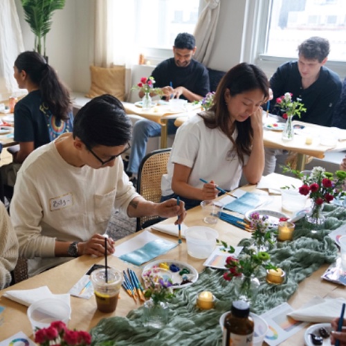 Guests painting small watercolor landscapes at long tables